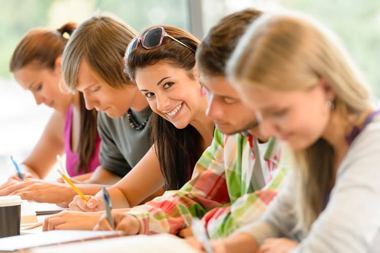 Students writing at high-school exam teens study
